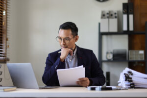 Serious executive businessman is busy with paperwork on the table in the office.